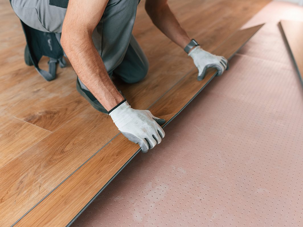 Handwerker verlegt Klick-Vinyl- oder Laminatboden auf Trittschalldämmung