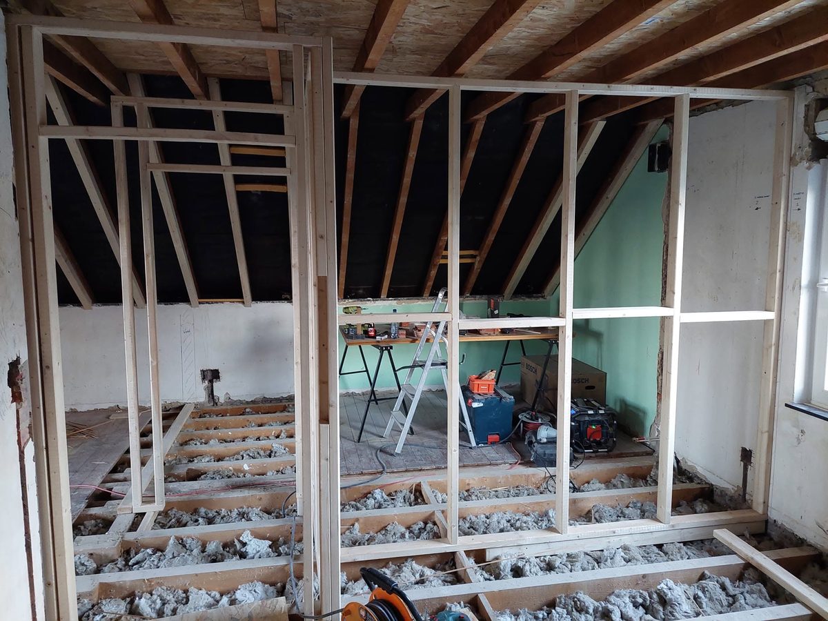 Holzständerwand beim Ausbau eines Dachgeschosses, im Boden liegt Dämmwolle