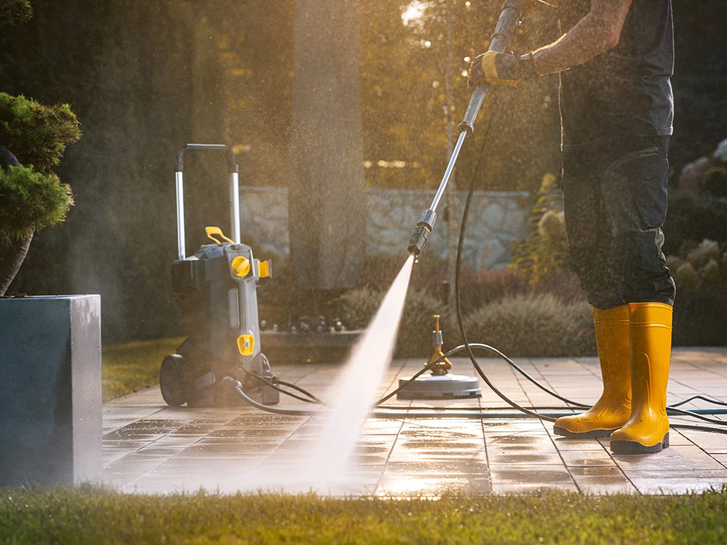 Terrasse wird im Abendlicht mit einem Hochdruckreiniger gereinigt